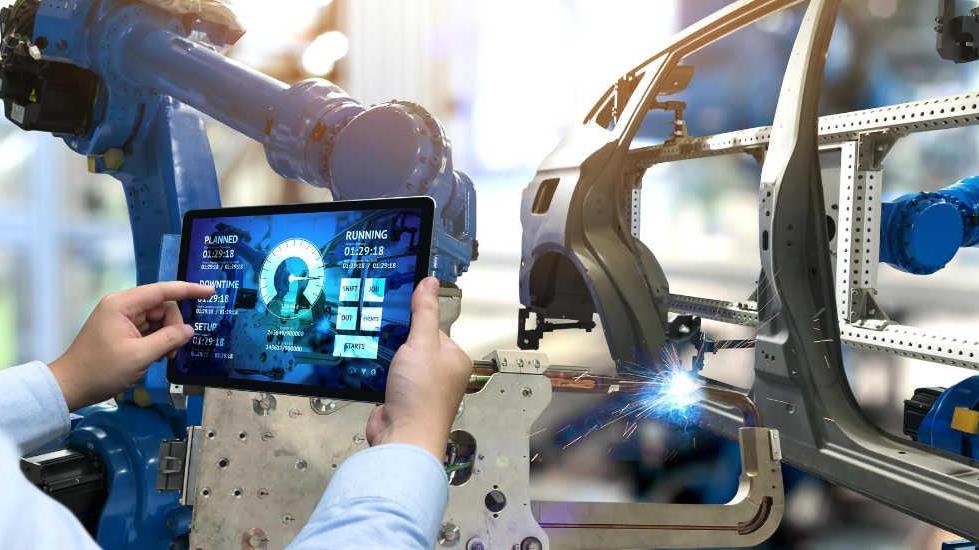 factory professional using a portable electronic device to interface with autonomous factory equipment