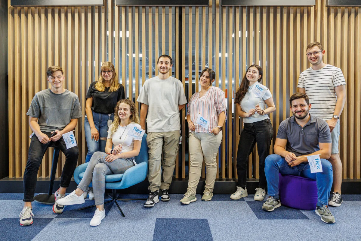 Foto grupal de pasantes del Flex sentados y de pie junto a una pared