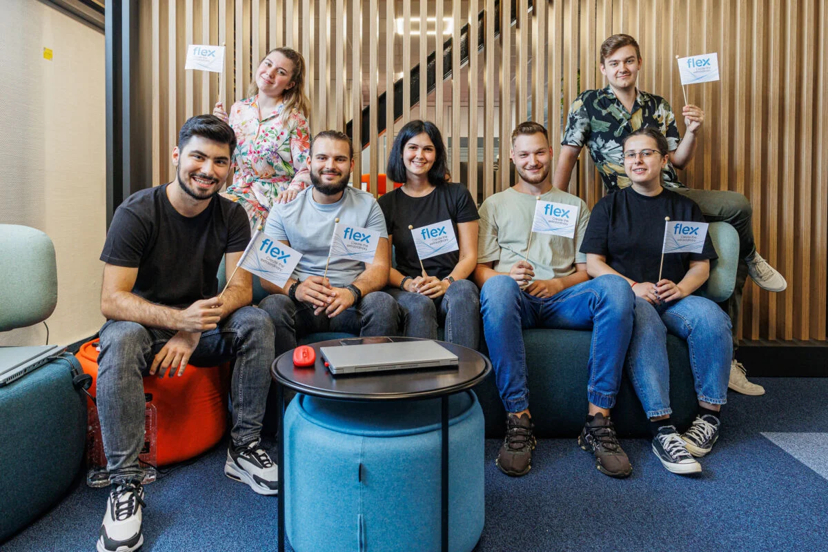Foto de grupo de pasantes del Flex sentados en un sofá sosteniendo banderas del Flex